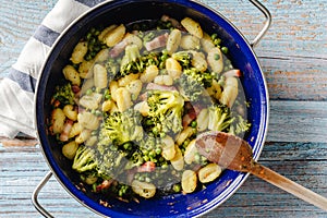 Top view on fresh prepared broccoli with gnocchi in casserole dish on the wooden table - homemade healthy food in bright light