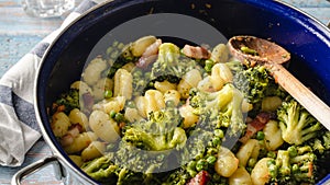 Top view on fresh prepared broccoli with gnocchi in casserole dish on the wooden table - homemade healthy food in bright light