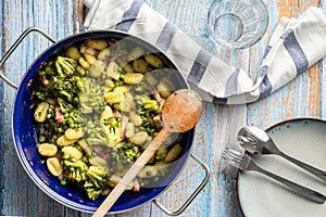 Top view on fresh prepared broccoli with gnocchi in casserole dish on the wooden table - homemade healthy food in bright light