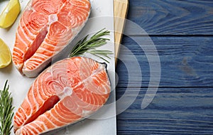 Top view of fresh raw salmon with lemon and rosemary on wooden table, space for text. Fish delicacy