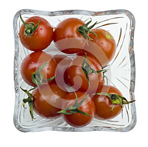Top view of fresh red cherry tomatoes with a water drops in a glass bowl isolated on a white background
