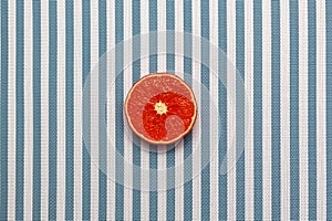 Top view of fresh red orange slice fruit on white blue striped background. Minimal style, food concept, flat lay