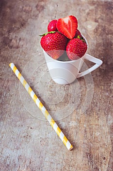 Top view of strawberries in a white cup on wooden background