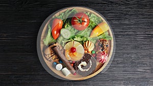 Top view of fresh ripe fruits with vegetables and assorted sweets junk food on wooden table. Concept of choosing vitamin