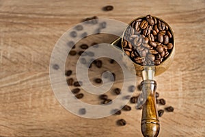 Top view of fresh roasted coffe beans in  cezve traditional turkish coffee pot on wooden table. Selective focus