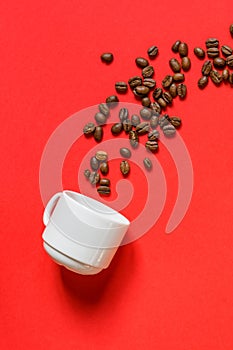 Top view of fresh roasted coffe beans and whte cup on red background. Flat lay