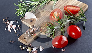 Top view of fresh rosemary, various kinds of spieces on cutting board , black background