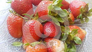 Top view of fresh strawberries in plate on rustic white wood background