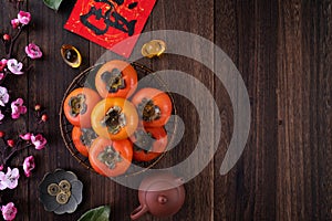 Top view of fresh sweet persimmons with leaves on wooden table background for Chinese lunar new year