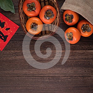 Top view of fresh sweet persimmons with leaves on wooden table background for Chinese lunar new year