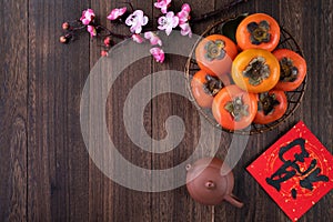 Top view of fresh sweet persimmons with leaves on wooden table background for Chinese lunar new year