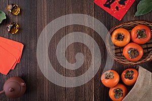 Top view of fresh sweet persimmons with leaves on wooden table background for Chinese lunar new year