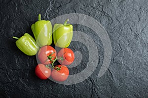 Top view of fresh vegetables. Pile of tomatoes and pepper on black background