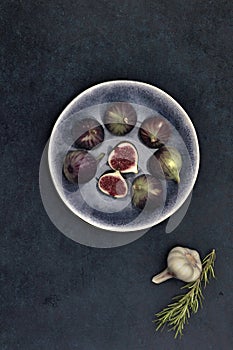 Top view fresh whole and cut half figs lay on plate by garlic head and fir isolated with side studio lightning