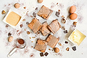 Top view of freshly baked home made brownie cake arranged with recipe ingredients over white rustic background