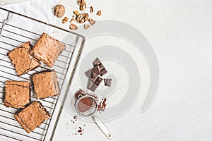 Top view of freshly baked home made brownie cake arranged with recipe ingredients over white rustic background. Copy space