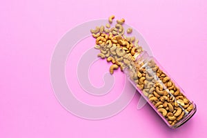 Top view fried cashew nut with salt on pink background. Copy space for text or design