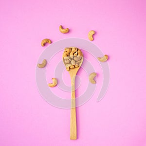 Top view fried cashew nut with salt on pink background. Copy space for text or design