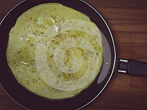 Top view of a fried fresh omelet in a frying pan. Omelet is made from milk and chicken eggs