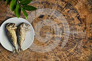 Top view fried mackerel on a white plate with real wooden table with copy space for text or design. Fried fish on the dish