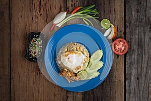 Top view of fried rice with egg on top, pork crackling and cucumber