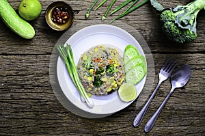 Top view fried rice in a white plate with spoon and fork on old wood table, Broccoli, scallions, melons than lemons are a