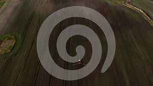 Top view frome drone of a red tractor plows the ground