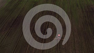 Top view frome drone of a red tractor plows the ground