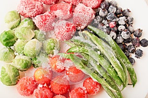 Top view of frozen foods in a plate - strawberries with shadberry and brussels sprouts with asparagus beans