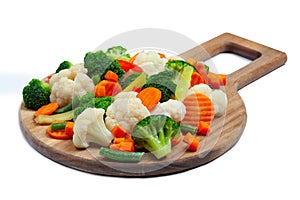 Top view of frozen mixed vegetables cauliflower, carrots, broccoli, sliced bell peppers lying on wooden cutting board photo