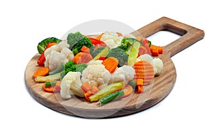Top view of frozen mixed vegetables cauliflower, carrots, broccoli, sliced bell peppers lying on wooden cutting board