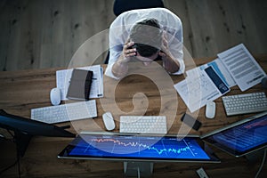 Top view of frustrated businessman with computer working at desk. Financial crisis concept.