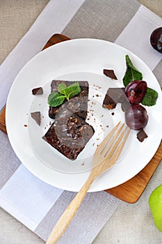 Top view of Fudge Brownie with Fresh Plum on Plate with Wooden Fork