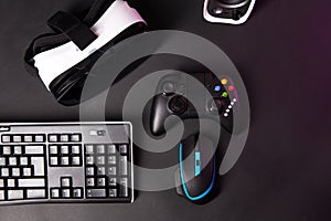 Top view a gaming gear, mouse, keyboard, joystick, headset, VR Headset on black table background.