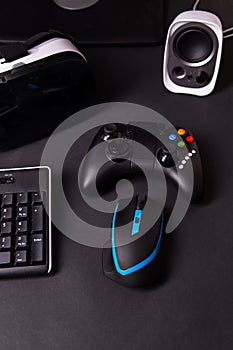 Top view a gaming gear, mouse, keyboard, joystick, headset, VR Headset on black table background.