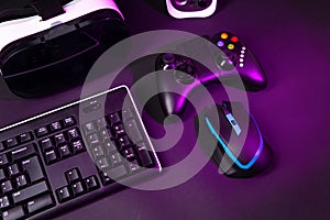 Top view a gaming gear, mouse, keyboard, joystick, headset, VR Headset on black table background.