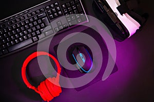 Top view a gaming gear, mouse, keyboard, joystick, headset, VR Headset on black table background.