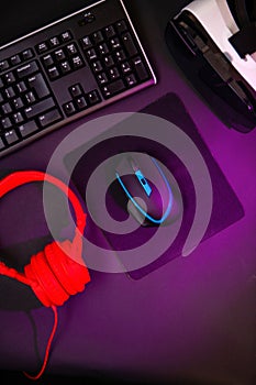 Top view a gaming gear, mouse, keyboard, joystick, headset, VR Headset on black table background.