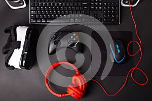 Top view a gaming gear, mouse, keyboard, joystick, headset, VR Headset on black table background.