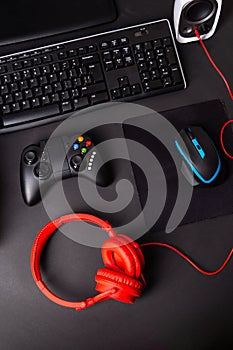 Top view a gaming gear, mouse, keyboard, joystick, headset, VR Headset on black table background.