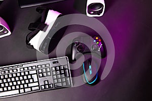 Top view a gaming gear, mouse, keyboard, joystick, headset, VR Headset on black table background.