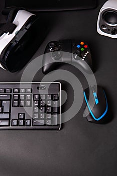 Top view a gaming gear, mouse, keyboard, joystick, headset, VR Headset on black table background.