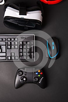 Top view a gaming gear, mouse, keyboard, joystick, headset, VR Headset on black table background.