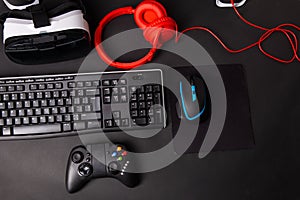 Top view a gaming gear, mouse, keyboard, joystick, headset, VR Headset on black table background.