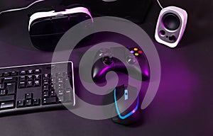 Top view a gaming gear, mouse, keyboard, joystick, headset, VR Headset on black table background.