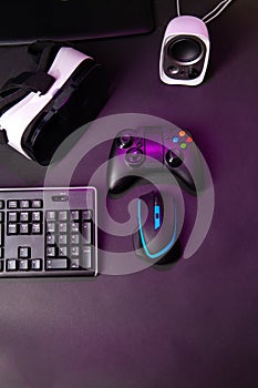 Top view a gaming gear, mouse, keyboard, joystick, headset, VR Headset on black table background.