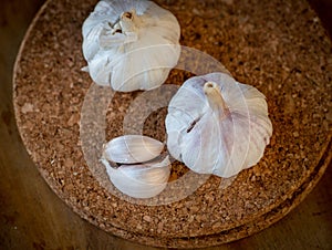 Top view of garlic bulb and cloves on a round cork board