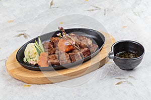 top view of Garlic Saikoro Steak: medium rare dice wagyu topping with mince carrot on hot plate served with potato salad.