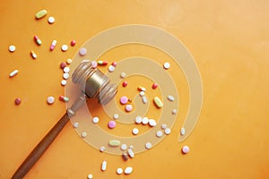 Top view of gavel, and medical pills on orange background