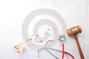 Top view of gavel, stethoscope and pills on white background